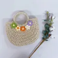Detailaufnahme der handgewebten Strohtasche mit bunten Häkelblumen-Verzierungen - Fünf Häkelblumen-Beige