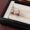 Detalle de pendientes de gota plateados con estampado de leopardo en una caja para joyas - Pendientes de aro-Plata