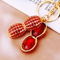 Peanut shaped keychain with red rhinestones and gold plating on warm background - Red Rhinestone Peanut