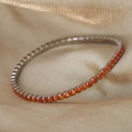 Elegante pulsera de titanio chapado en oro con circonitas naranjas sobre fondo de seda - Color Acero/Circonita Naranja