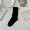 Minimalistische zwarte katoenen kuitkousen met elastische boorden op een witte tafel - Zwart