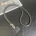 Close-up of black metal and crystal crossbody phone strap with transparent pad on leather - Gray