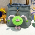 Green plush monster keychain with big pink lips hanging on a denim bag as a cute accessory - Green
