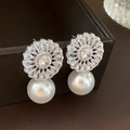 Macro view of flower-shaped zircon earring with a large white hanging pearl detail - Silver Pin - Gold Zirconia Flower Drop Earrings