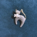 Silver frosted cat brooch with golden tail bow and white pearl accent on blue fabric - Christmas Cat Brooch