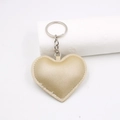 Detail shot of a golden heart-shaped leather keychain with fine stitching and metal ring - Gold