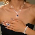 Sparkling silver jewelry set with blue pear gemstones and V-shaped necklace on a model - Three-Piece Set / Silver Light Blue