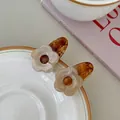 Détail de barrettes fleurs avec texture acrylique marbrée ambre et crème sur une assiette - Ambre