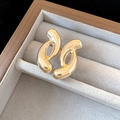Close-up of minimalist gold C-shaped earrings with polished finish in a velvet box - Gold Geometric Streamline