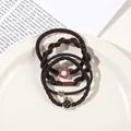Detail of coffee brown elastic hair ties set with heart and flower charms on a white plate - 4Pcs Set - Pineapple Style / Dark Coffee