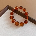 Detailed view of beaded bracelet with amber resin beads and gold metal spacers on tray - Bracelet / Brown