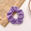 Paarse geribbelde kanten bloem scrunchie haarelastiek op vintage kranten achtergrond - Taro Paars