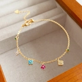 Macro detail of gold clover bracelet with colorful stones on wooden jewelry box surface - Bracelet - Gold