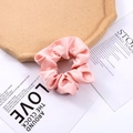 Close-up of pink faux silk satin scrunchie with soft fabric texture on vintage paper - Pink