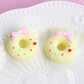 Macro shot of two resin donut charms with pink bows and colorful sprinkles on a tray - Small Bow - Yellow Base + Pink