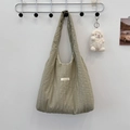 Close-up of olive green pleated tote bag with a white plush lamb keychain on a metal hanger - Gray