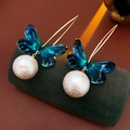 Detalle macro de pendientes de mariposa azul con perlas blancas y ganchos dorados - Gancho de Oreja-Azul