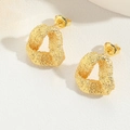 Golden triangle stud earrings with textured grain finish on a neutral background - Hollow Geometric Style