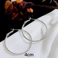Dettaglio di orecchini a cerchio in argento satinato da 4cm su sfondo nero e tessuto - 4cm