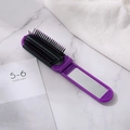 Violette faltbare Reisehaarbürste mit Spiegel und schwarzen Borsten auf Marmor - Lila