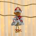 Dettaglio di un orsetto di peluche natalizio con cappello a scacchi e campanelli d'oro - Orso