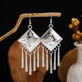 Detailed view of silver ethnic leaf tassel earrings hanging on a natural wooden branch - Silver Rhombus Relief Multi-Tassel Style (E2873-7)