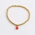 Gold beaded stretch bracelet featuring a colorful enamel evil eye charm on white background - Red