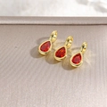 Detailed view of three red teardrop pendants with 18k gold plating on textured metal base - Red