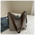 Dettaglio della borsa in tela grigia con tracolla marrone e etichetta moda sobria - Grigio