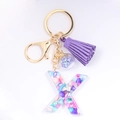 Detail of letter X resin keychain with purple tassel, colorful stones, and star charm - Letter X