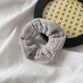Detailed view of light gray knitted scrunchie with soft ribbed plush texture on linen - Gray
