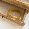 Close-up of amber marble resin bangle with translucent texture in a vintage wooden drawer - Inner Diameter 66mm / Transparent Yellow