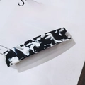Makro-Detail der rechteckigen Acetat-Haarklammer mit schwarz-weißem Marmormuster-Design - Kuhmuster