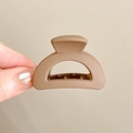 Matte brown shark hair claw clip for high ponytail styling held against a beige wall - 17# Coffee 4CM Matte Arc Style