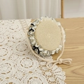 Detail of round straw bag with white lace trim and black ribbon bow for summer - Circular Straw Bag / Bag-Beige