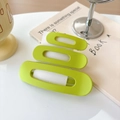 Close-up of vibrant lime green matte hair clip with triple oval cutout design on a desk - Yellow-Green