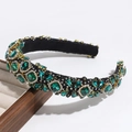 Macro shot of luxury green rhinestone headband with gold settings on a wooden tray - Green