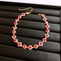 Detalle de collar vintage dorado con piedras rojas facetadas y motivos de trébol - Collar-Dorado-Rojo