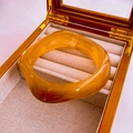 Amber resin cuff bracelet with translucent wavy design in a luxury jewelry box - Amber Streamline Resin Bangle