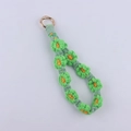 Close-up of handmade woven daisy wristlet with green petals and gold spring clasp - Green