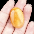 Oval yellow crystal agate gemstone held in hand showing natural translucent texture - Yellow Jade
