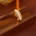 Detail of gold-plated hollow lace ring with elegant pearls on dark wooden stand - Gold