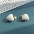 Detail of heart-shaped white stone pendants with gold clasps on blue textured leather - White Turquoise