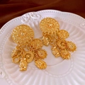 Macro shot of vintage gold earrings with sun and coin charms on a ceramic plate - Floral Embossed Style (1#) / Gold