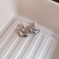 Detailweergave van zilveren waterdruppel clip-on oorbellen op een crème tray - Clip-on Stijl / Zilver