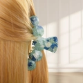 Detail of a large blue-green marble hair claw clip on blonde hair with golden highlights - Style A Arch (Blue-Green Marble)