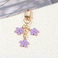 Golden keychain featuring three purple enamel flower pendants and lobster clasp - Purple