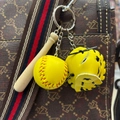 Close-up of mini baseball keychain with wooden bat and yellow glove on a bag strap - 3.5CM Yellow/Black Strap