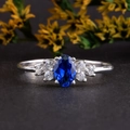 Elegante zilveren ring met ovale blauwe saffier en zirkonen op een donkere stenen basis - US 7 / Blauw