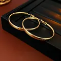 Detail von hochglanzpolierten goldenen Creolen auf einem schwarzen Ledertablett - Glatte Creolen (Silberstift) / Gold